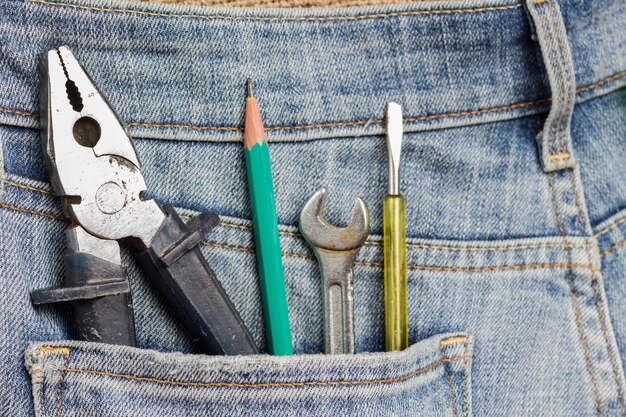 Pinces et autres outils de travail dans la poche de jeans.