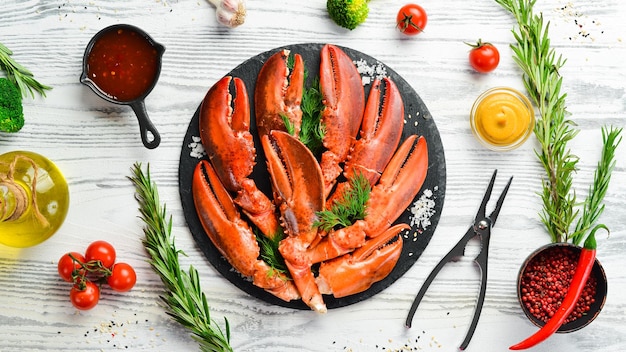 Pinces de homard bouillies avec des épices et du persil sur une plaque de pierre noire Sur fond blanc Délices de fruits de mer de style rustique