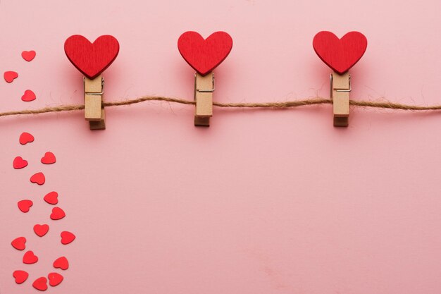 pinces à linge en bois avec des coeurs sur une corde sur fond rouge