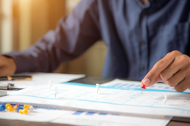 Épingle à la main sur le calendrier de bureau avec équipement de bureau