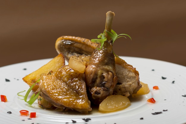 Pintade rôtie avec pommes de terre, aux herbes vertes, posée sur une plaque blanche