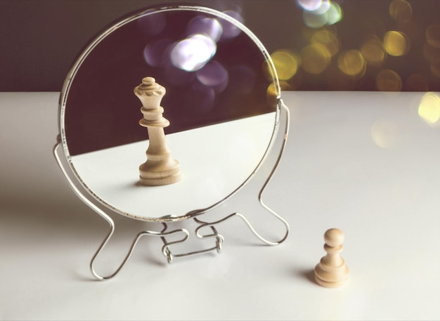 Pion d'échecs regardant dans le miroir et voyant une reine