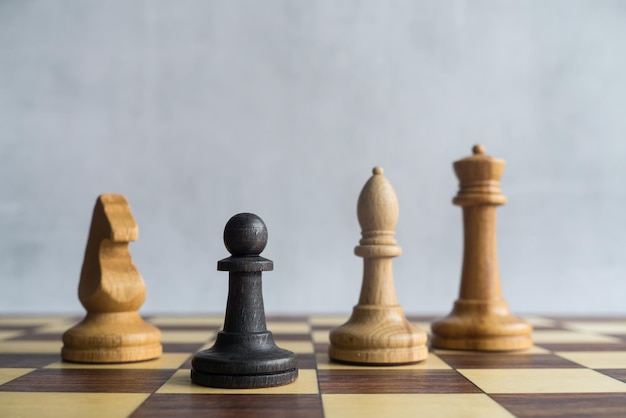 Un pion noir entouré de figures d'échecs blanches