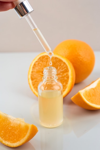 Pipeter avec de l'huile essentielle d'orange sur une bouteille et des oranges. Concept de médecine naturelle. Aromathérapie