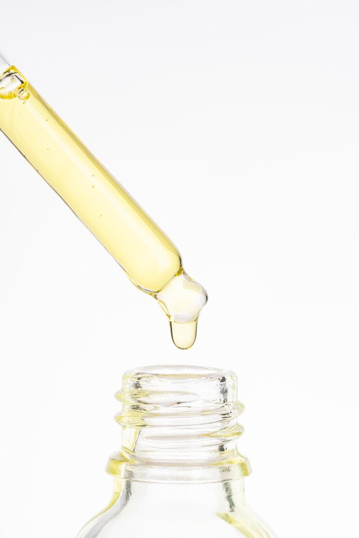 Photo pipette cosmétique avec goutte huileuse jaune gros plan sur fond blanc goutte de beauté d'huile d'or luxueuse ou de sérum huileux dégoulinant de pipette en verre dans la bouteille