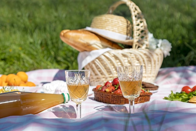 Pique-nique dans le parc vin blanc dans des verres et baguettes dans un panier