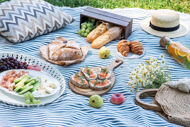 Pique-nique d'été sur l'herbe, sandwichs au saumon, raisin, boulangerie et fruits