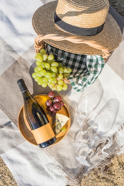 Photo pique-nique d'été sur la plage avec du vin, du fromage et des raisins. vue de dessus avec un espace de copie. orientation verticale.