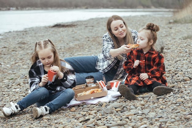 pique-nique familial à l'extérieur de la ville près de la rivière maman et deux filles