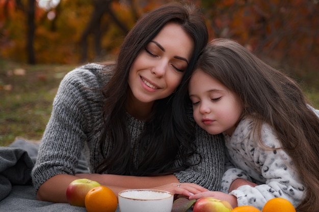 Pique-nique familial à l'heure d'or d'automne. Mère avec enfant fille buvant du chocolat chaud ou du thé à l'extérieur à la saison d'automne.