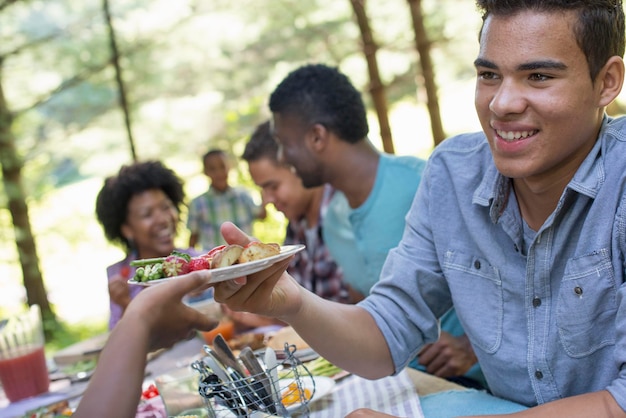 Un pique-nique en famille à l'ombre des grands arbres Parents et enfants se servant de fruits frais