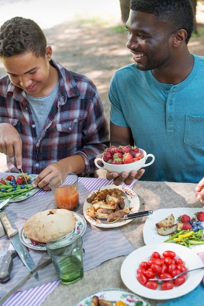 Un pique-nique en famille à l'ombre des grands arbres Parents et enfants se servant de fruits frais