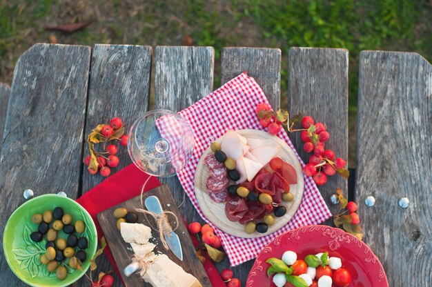 Pique-nique italien avec vin rouge, parmesan, jambon, salade caprese et olives. Déjeuner en plein air et table en bois. Collations traditionnelles. Espace copie