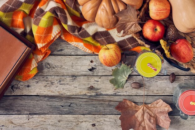 Pique-nique rustique en automne avec des pots de maçon à carreaux et des fruits d'automne sur des planches en bois