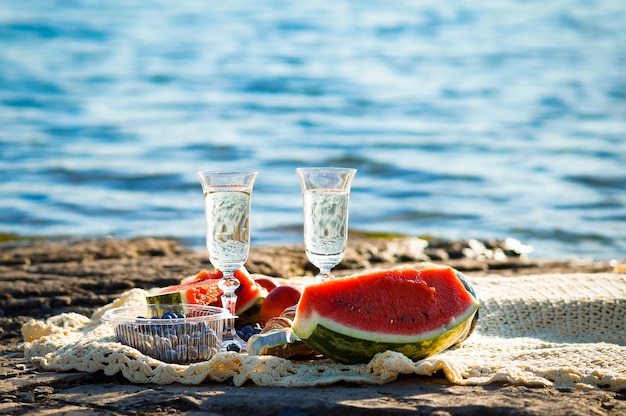pique-niques de vacances au bord de la mer deux verres de champagne, myrtilles, pastèque et croissants