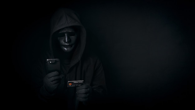 Un pirate informatique anonyme dangereux utilise un smartphone et une carte de crédit, brise les données de sécurité et pirate le mot de passe