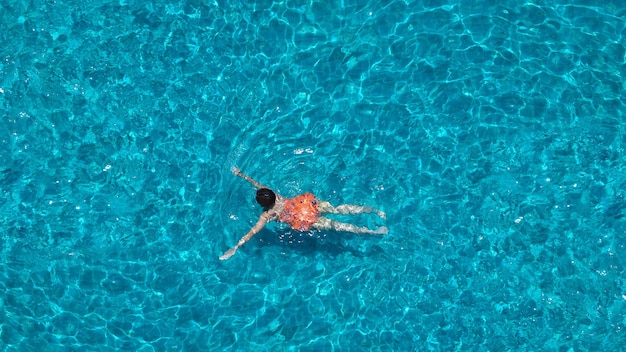 Piscine de couleur bleue eau claire et personnes profitant d'une journée ensoleillée d'été et d'un angle de vue de dessus.