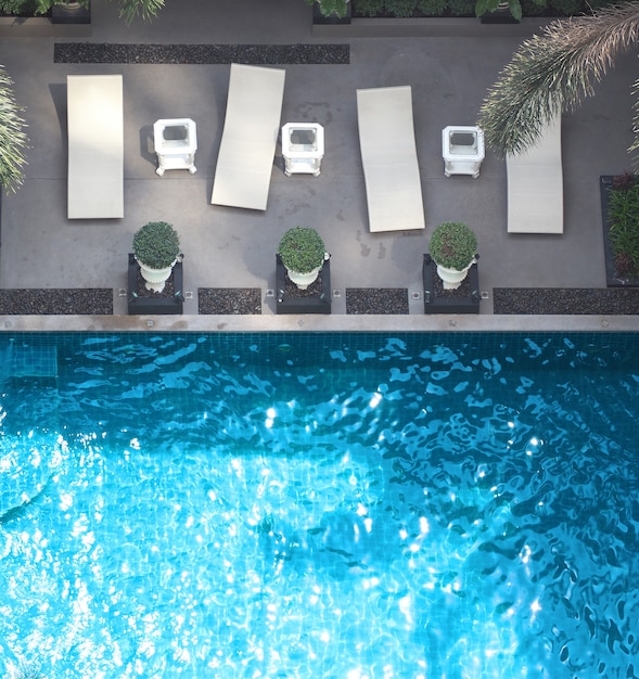 Piscine eau bleue en été et lits de plage blancs et angle de vue de dessus.