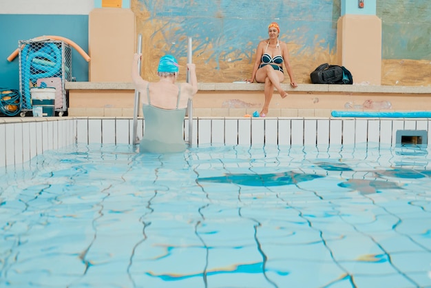 Piscine de nageur et femme quittant l'eau après un exercice aquatique de natation amusant et une formation pour l'entraînement physique dans un spa Des amis âgés se détendent et profitent de la natation pour la santé dans la piscine intérieure ensemble