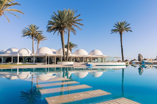 Piscine et palmiers avec bâtiment traditionnel avec toit en forme de dôme Tunisie