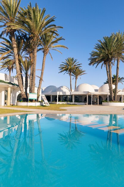 Piscine et palmiers avec bâtiment traditionnel avec toit en forme de dôme Tunisie