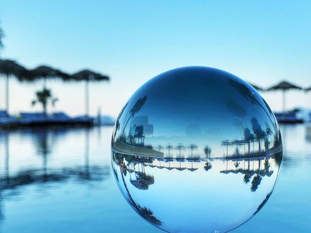 Piscine avec des palmiers sur un horizon reflété dans une boule de verre