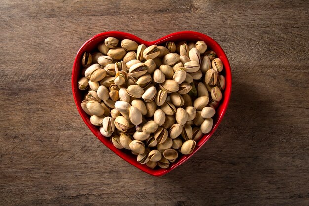 pistaches dans un bol coeur avec fond en bois.