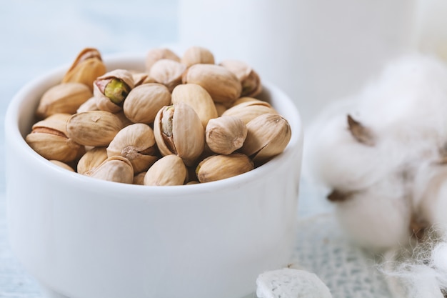 Pistaches dans une tasse en céramique blanche sur un blanc