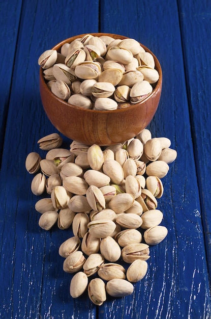 Pistaches entières dans un bol et près d'une table en bois bleue