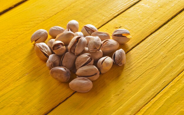 Pistaches sur une table en bois de couleur jaune.