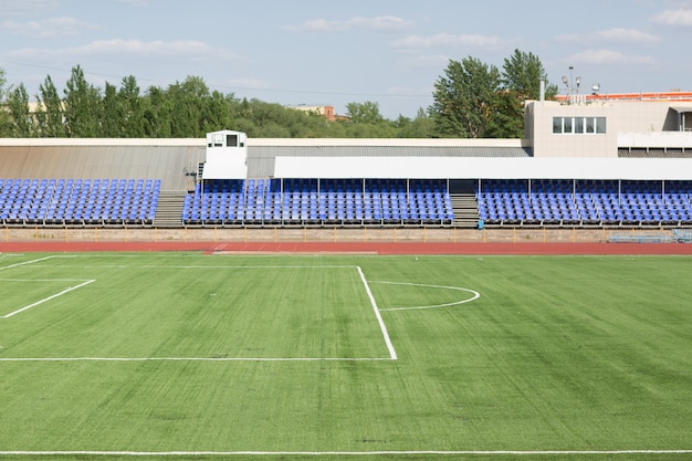 Piste de course et terrain avec de l'herbe verte pour le football au stade.