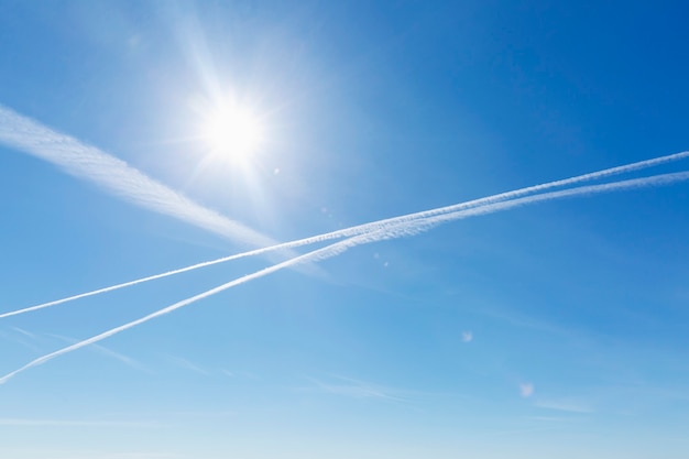 Photo pistes d'avions et traînées chimiques dans le ciel bleu clair.