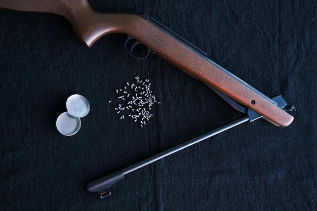 Pistolet à fusil cassé en deux avec des pastilles d'air pour la chasse sur fond sombre en tissu