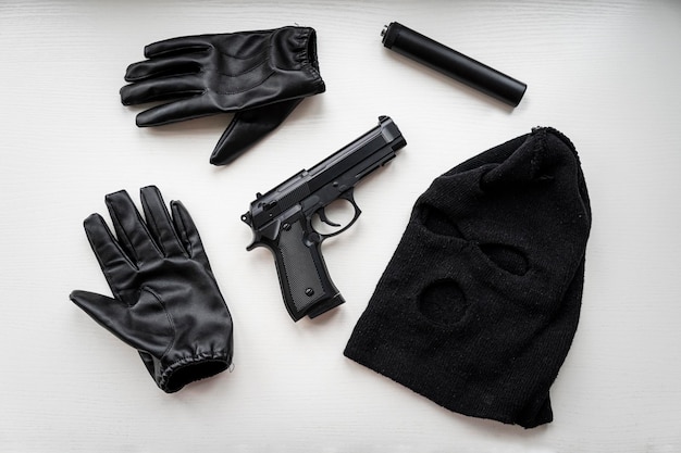 Pistolet à gants et masque noir sur un tableau blanc Preuve lors de la recherche d'un voleur ou d'un meurtrier preuve d'un crime