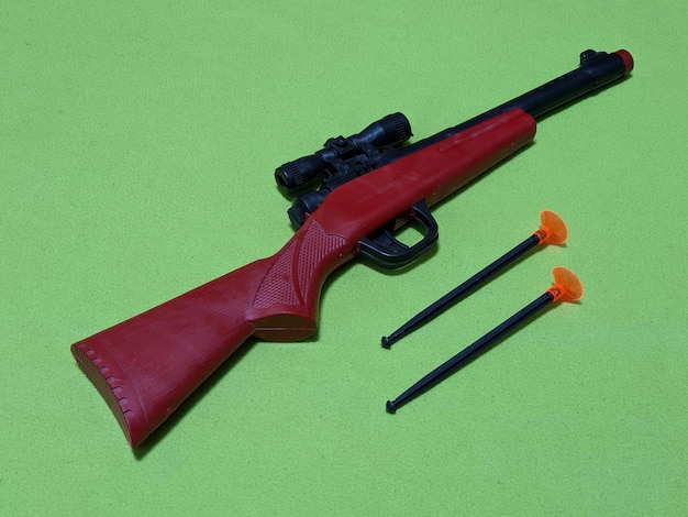 Un pistolet jouet rouge sur fond vert