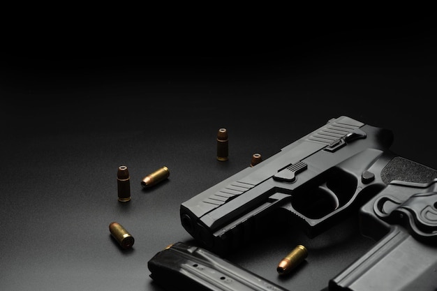 Le pistolet noir est placé sur un fond sombre avec des munitions de 9 mm placées Et une radio de police avec