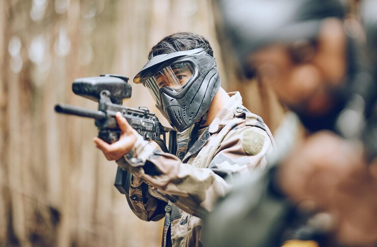 Photo pistolet de paintball et cible avec homme sports et action champ de bataille en plein air et concentration de soldat pendant le jeu de guerre arme de but de sport extrême et exercice de mission militaire et fitness avec l'équipe