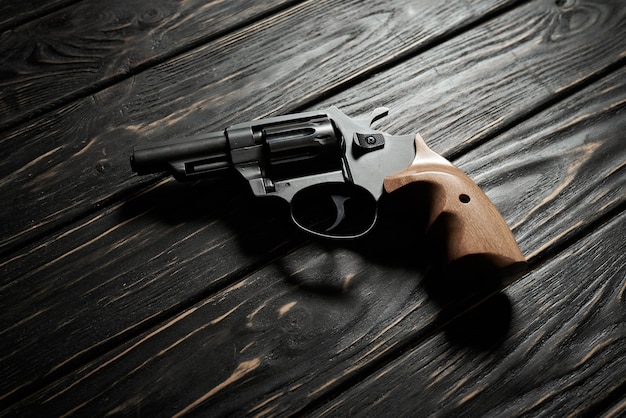 Pistolet revolver noir sur fond de bois foncé