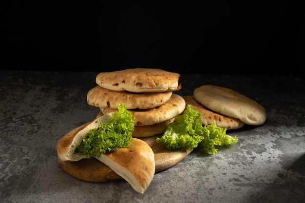 Pitas disposés sur une planche de bois, épinards sur fond sombre