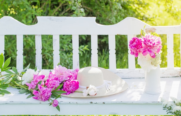 Pivoine en cruche sur banc en bois blanc dans le jardin d'été