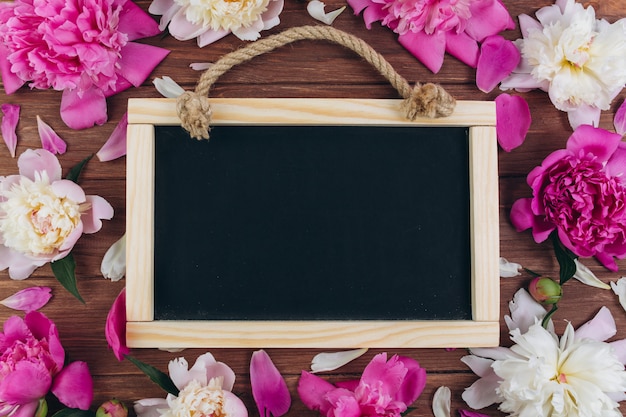 Pivoines Roses Et Blanches Autour De Tableau Noir Sur Un Fond En Bois.