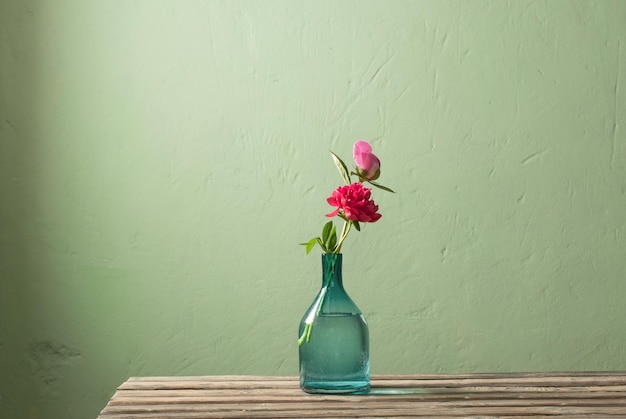 Pivoines roses dans un vase en verre sur fond vert