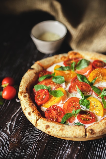 Pizza appétissante avec des tomates et du fromage sur un fond en bois foncé