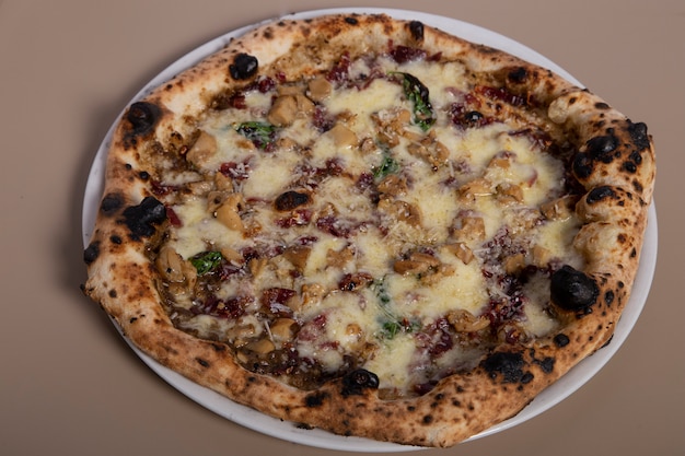 Pizza artisanale napolitaine avec mozzarella, saucisse, truffe noire, basilic, poivre noir et parmesan. Vue de dessus.