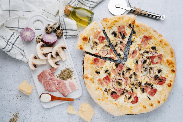 Pizza au bacon et aux champignons sur une table à côté des matières premières Vue de dessus