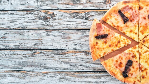 Pizza au bacon tomates fumées et fromage mozzarella Cuisine italienne Sur un fond en bois Espace libre pour le texte Vue de dessus