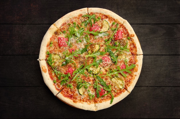 Pizza au boeuf, courgettes, poivrons et pois verts sur fond de bois