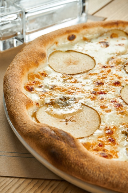 Pizza au four appétissante avec sauce blanche, poire et fromage gorgonzola croustillant sur une table en bois. Réglage de la table du restaurant. Gros plan, mise au point sélective