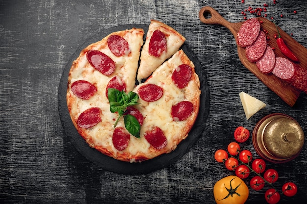 Pizza au fromage et au salami sur une pierre et un tableau noir