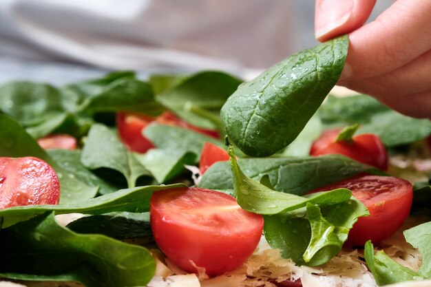 Pizza au fromage, tomates, épinards et saucisse fumée